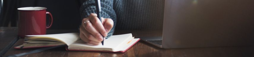 Person's hand writing with a pen in a journal
